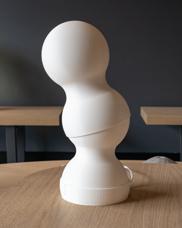 White abstract sculpture on a wooden table with a dark background