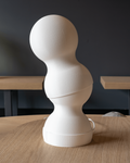 White abstract sculpture on a wooden table with a dark background