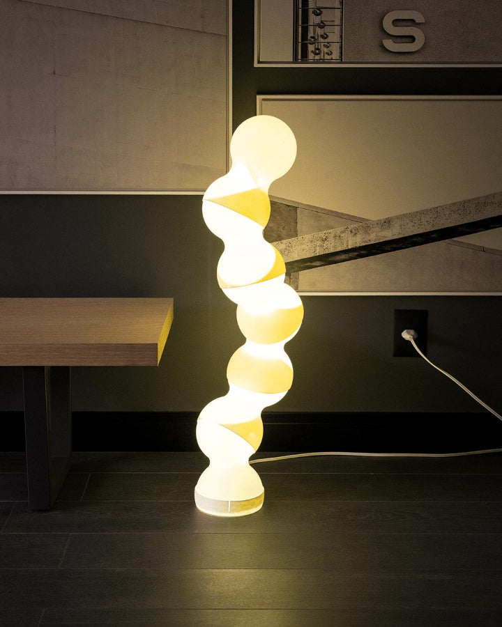 Spiral-shaped floor lamp with a warm glow in a modern interior setting.