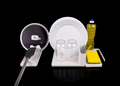 Dish drying rack with plates, glasses, and a bottle of dish soap on a black background