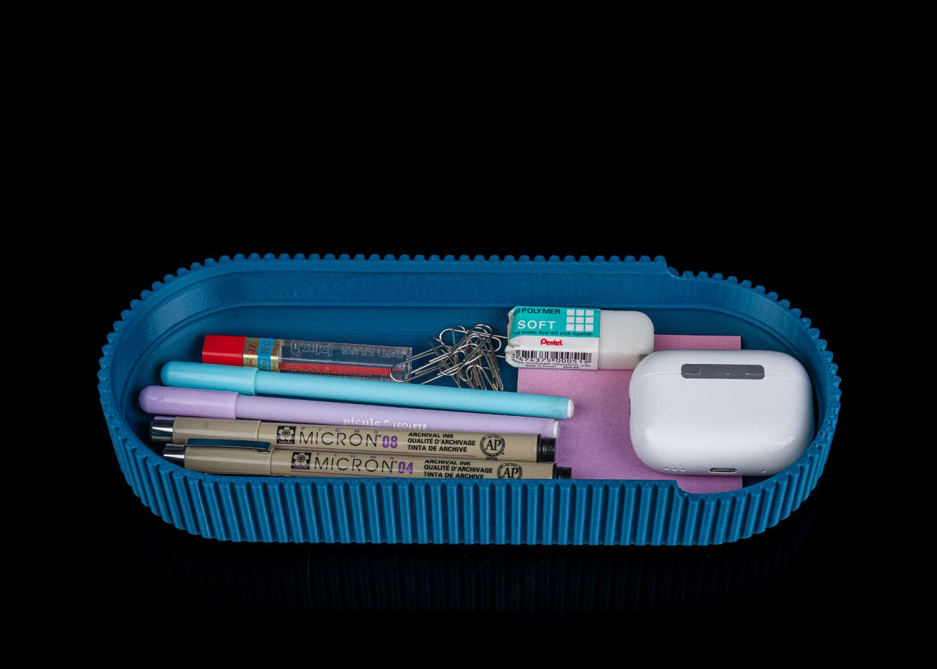 Blue pencil case with stationery items on a black background
